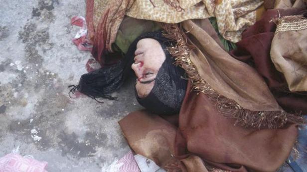 Eine tote Frau liegt auf dem Boden, teilweise mit Tüchern bedeckt.