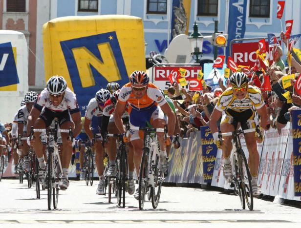 Radrennfahrer liefern sich ein spannendes Kopf-an-Kopf-Rennen vor jubelnden Zuschauern.