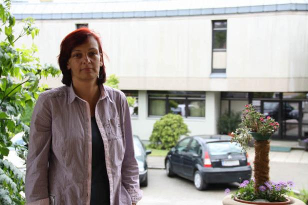 Eine Frau steht vor einem Gebäude mit geparkten Autos.