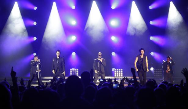 Die New Kids on the Block treten vor einem jubelnden Publikum auf einer Bühne auf.