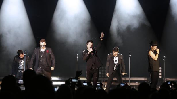 Die New Kids on the Block treten auf einer Bühne vor Publikum auf.