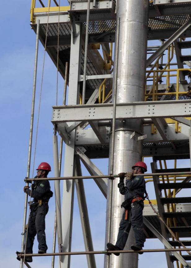 Zwei Arbeiter mit Schutzhelmen stehen auf einer Metallkonstruktion.