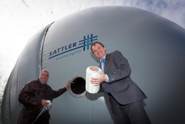 Zwei Männer stehen vor einer großen, grauen Sattler-Tex-Halle.