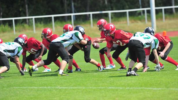 American-Football-Spieler stehen sich auf einem grünen Feld gegenüber.