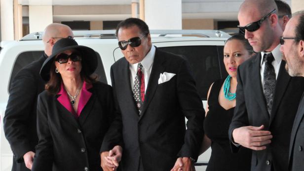 Muhammad Ali wird von seiner Frau und Sicherheitsleuten begleitet.