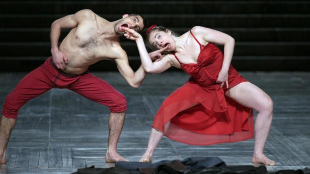 Ein Mann und eine Frau in roter Kleidung führen eine ausdrucksstarke Tanzperformance auf.