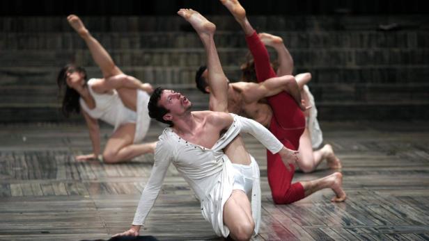 Mehrere Tänzer führen eine anspruchsvolle Choreografie auf einer Bühne auf.