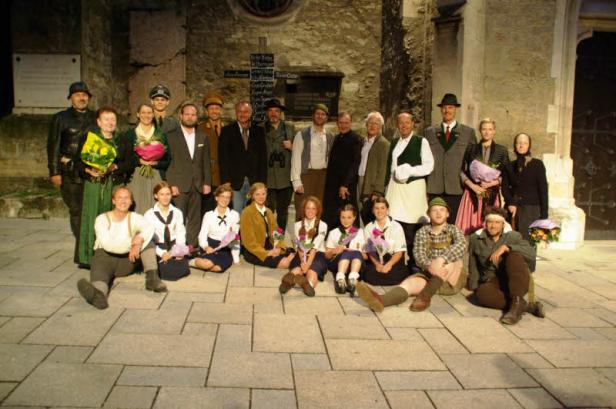 Eine Gruppe von Menschen posiert vor einem Gebäude mit einer Gedenktafel.