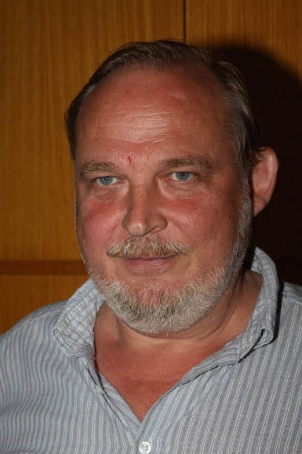 Porträt eines Mannes mit Bart und blau-grauen Augen.