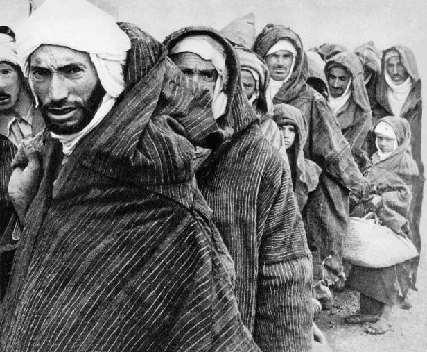 Eine Gruppe nordafrikanischer Menschen in traditioneller Kleidung steht zusammen.