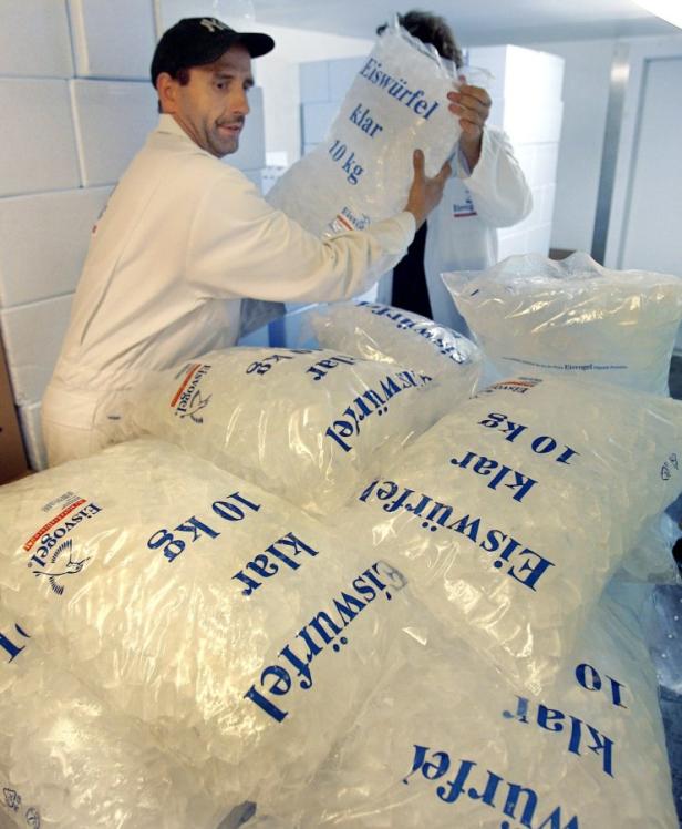 Zwei Arbeiter hantieren mit Säcken voller Eiswürfel der Marke Eisvogel.