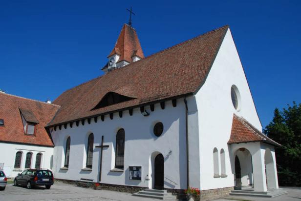 Eine weiße Kirche mit einem roten Ziegeldach unter blauem Himmel.
