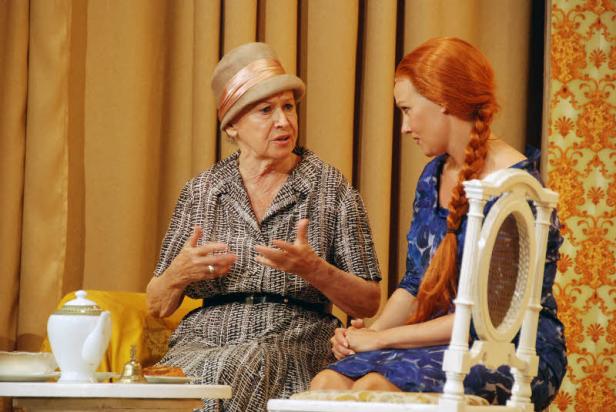 Zwei Frauen sitzen an einem Tisch mit Teegeschirr und unterhalten sich.