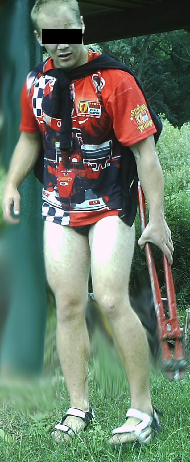 Ein Mann in Sandalen, Shorts und einem T-Shirt mit Rennwagenmotiv hält eine Bolzenschere.