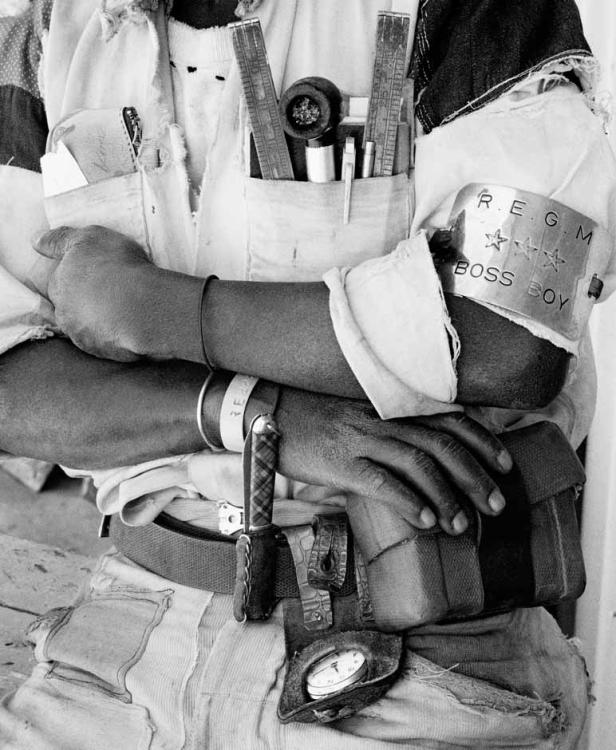 Ein Mann mit Werkzeugen in den Taschen und einem Armband mit der Aufschrift „Boss Boy“.