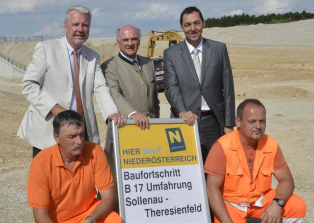 Eine Gruppe von Personen posiert vor einem Schild zum Baufortschritt der B17 Umfahrung Sollenau-Theresienfeld.