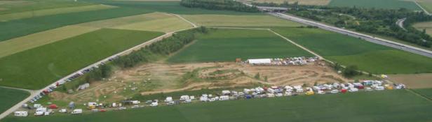 Luftaufnahme einer Motocross-Strecke mit parkenden Wohnmobilen und Autos.