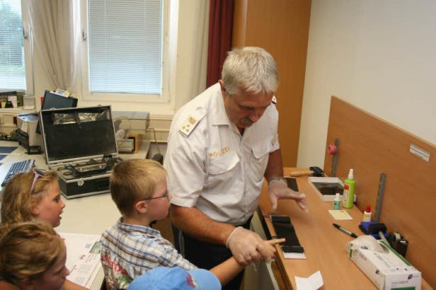 Ein Polizist erklärt Kindern die Spurensicherung.