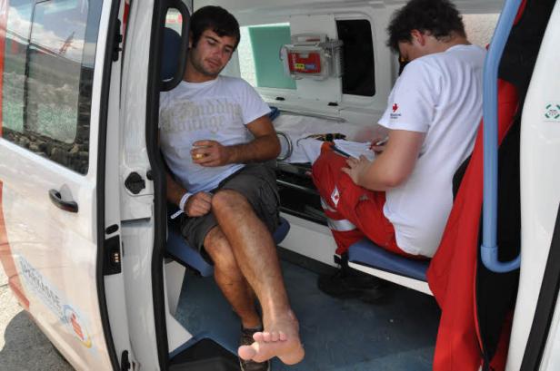 Ein Mann sitzt barfuß in einem Krankenwagen, während ein Sanitäter Notizen macht.