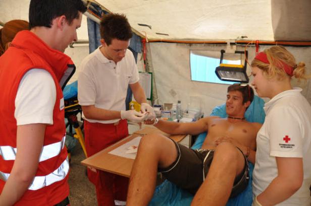 Ein Mann wird in einem Zelt von Sanitätern des Österreichischen Roten Kreuzes behandelt.