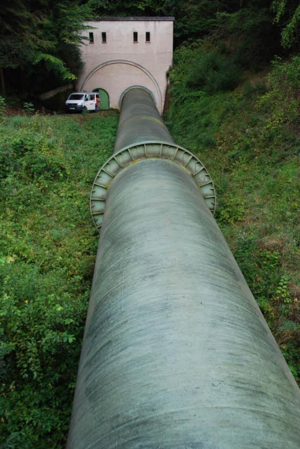Eine große Wasserleitung führt zu einem Gebäude am Hang.