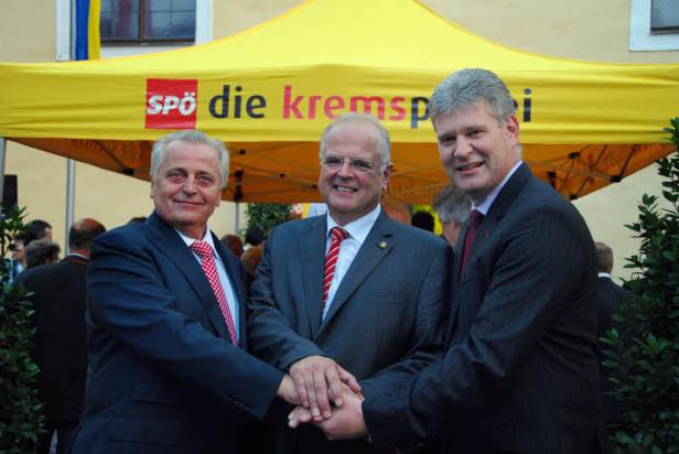 Drei Männer in Anzügen schütteln sich die Hände vor einem SPÖ-Zelt. Drei Männer in Anzügen schütteln sich die Hände vor einem SPÖ-Zelt.