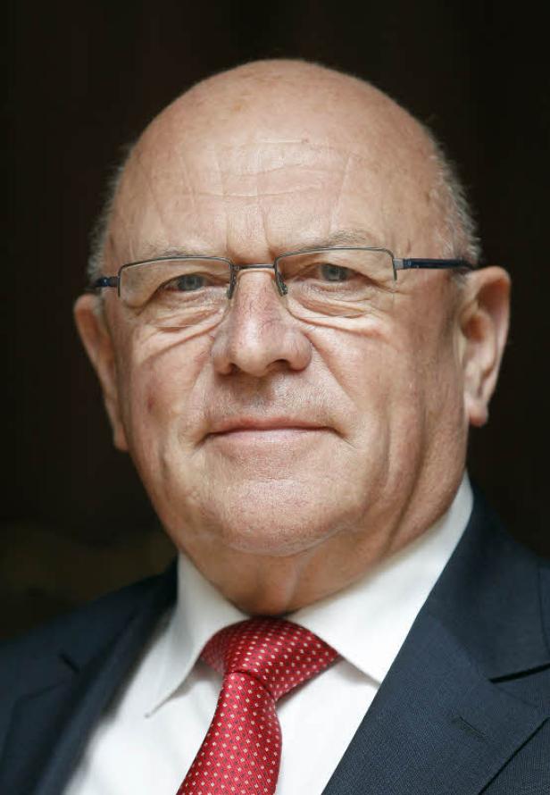Porträt eines Mannes mit Brille, Anzug und roter Krawatte.