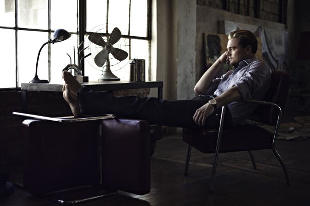 Leonardo DiCaprio entspannt barfuß in einem Sessel in einem Loft.