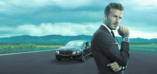 David Beckham posiert vor einem schwarzen Bentley in einer Wüstenlandschaft.