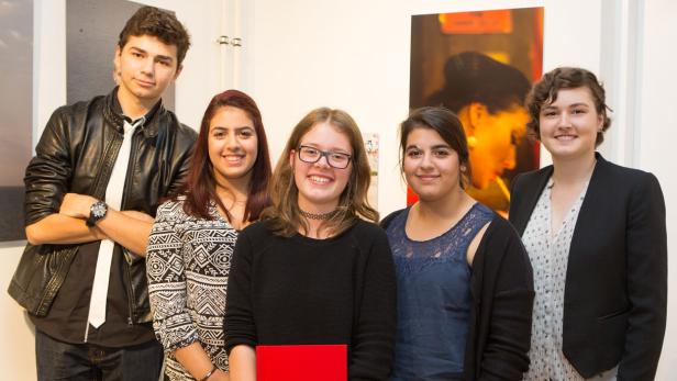 Fünf junge Leute posieren vor Kunstwerken in einer Galerie.