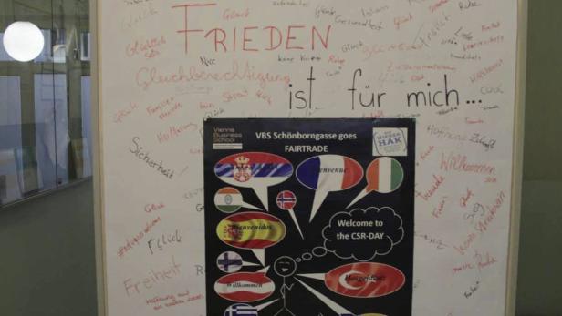 Ein Whiteboard mit den Wörtern „Frieden“, „Gleichberechtigung“ und anderen positiven Begriffen, sowie einem Fairtrade-Poster.