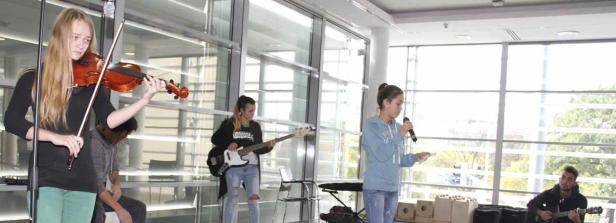 Eine Gruppe junger Leute spielt Musik in einem hellen Raum.