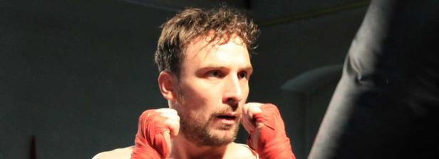 Ein Mann mit bandagierten Händen steht in Kampfposition.