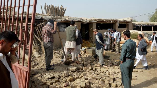 Eine Gruppe von Männern steht vor einem beschädigten Gebäude.