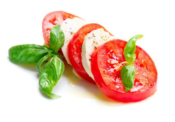 … Ein Caprese-Salat mit Tomaten, Mozzarella und Basilikum auf einem weißen Teller.