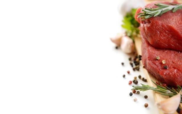 Kotelett.jpg Rohes Rindfleisch mit Rosmarin, Knoblauch und Pfefferkörnern auf einem Holzbrett.