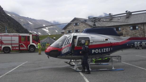 Ein Polizei-Hubschrauber steht neben einem Feuerwehrauto in einer Bergregion.