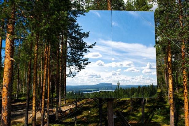 Ein großer Spiegel inmitten eines Waldes reflektiert den Himmel und die Landschaft.