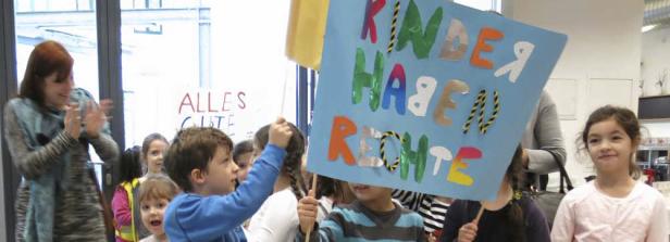 Eine Gruppe Kinder demonstriert mit selbstgemalten Schildern für Kinderrechte.
