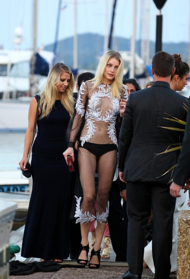 Eine Frau in einem transparenten Kleid mit floralen Verzierungen auf einem Event am Hafen.