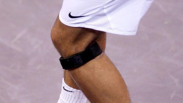 Das Bein eines Tennisspielers mit einer Kniebandage von Nike.