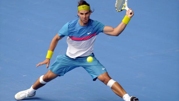 Rafael Nadal spielt Tennis auf einem blauen Platz.