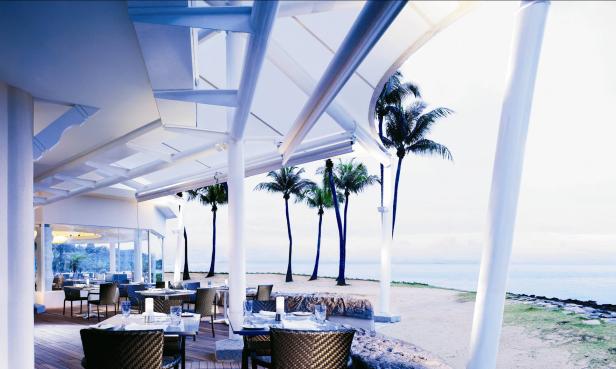 Ein Restaurant am Strand mit Palmen und Meerblick.