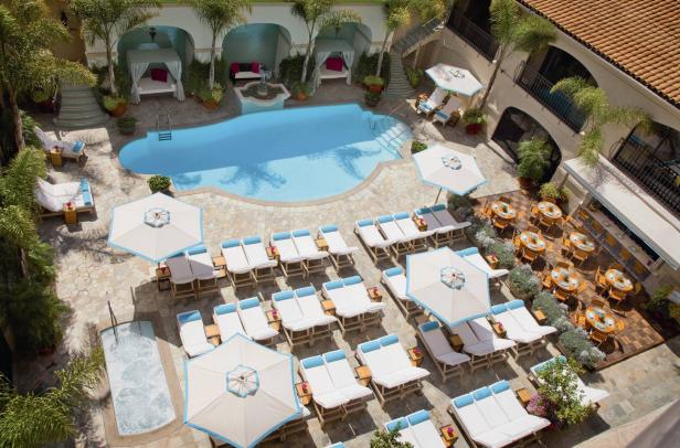 Ein Hotelpool mit Liegestühlen, Sonnenschirmen und Cabanas, gesehen von oben.