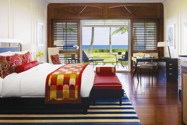 Ein Hotelzimmer mit Meerblick und einem Bett mit farbenfroher Tagesdecke.