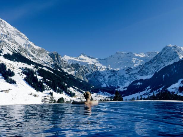 Eine Frau entspannt in einem Pool mit Blick auf schneebedeckte Berge.