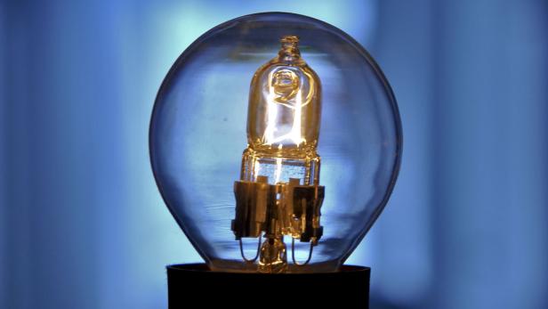 Eine eingeschaltete Halogenlampe vor einem blauen Hintergrund.