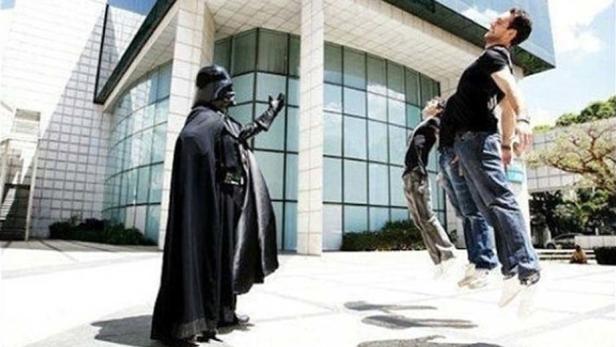 Darth Vader scheint seine Macht auf drei schwebende Personen vor einem Gebäude anzuwenden.