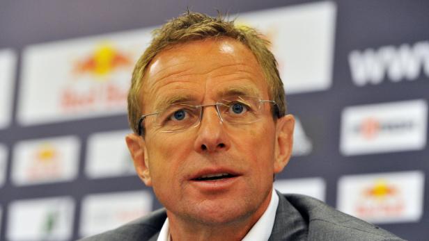 Ein Mann mit Brille und blonden Haaren vor einer Wand mit Logos.