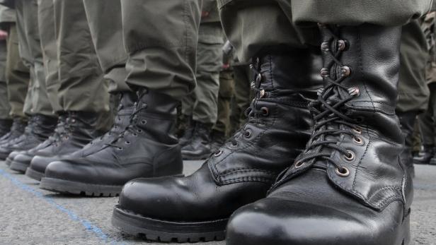 Eine Reihe von Soldaten in Uniform und schwarzen Stiefeln steht in Reih und Glied.